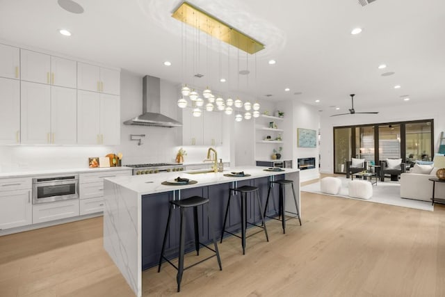 3005 French Pl, Austin, TX 78722 - kitchen with wall chimney range hood, appliances with stainless steel finishes, open shelves, light wood-style floors, and recessed lighting
