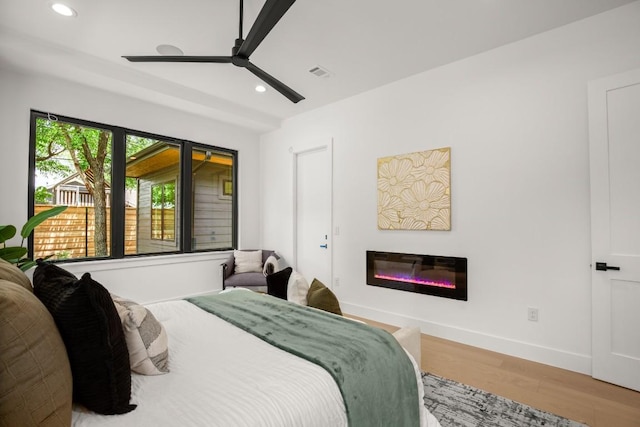 3005 French Pl, Austin, TX 78722 - bedroom with light wood-style flooring, recessed lighting, a glass covered fireplace, and a ceiling fan