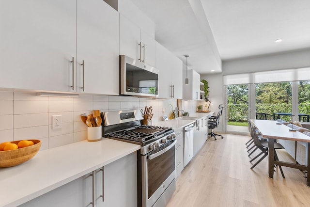 4004 Banister Ln Unit 105, Austin, TX 78704 - kitchen with stainless steel appliances, white cabinetry, backsplash, light wood-style flooring, and recessed lighting