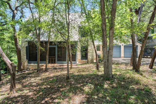 1703 Graywood Cv, Austin, TX 78704 - rear view of property featuring a sunroom, driveway, and an attached garage