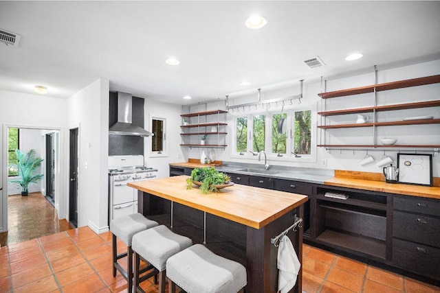 1703 Graywood Cv, Austin, TX 78704 - kitchen featuring wood counters, wall chimney range hood, open shelves, white gas stove, and recessed lighting