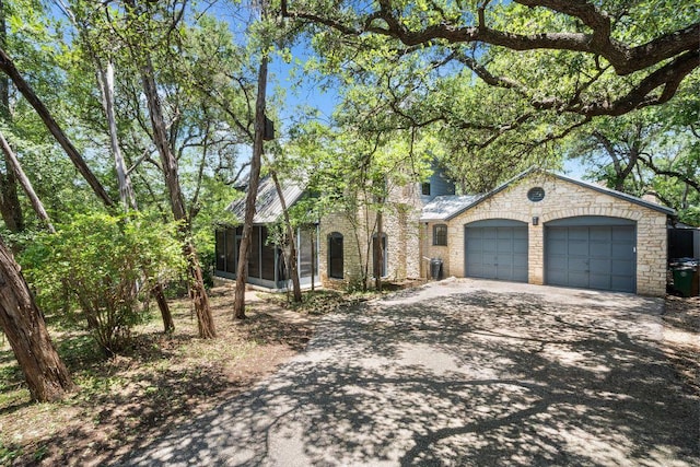 1703 Graywood Cv, Austin, TX 78704 - view of front of home with a sunroom, asphalt driveway, an attached garage, and a chimney