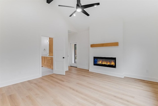 837 Birch Ln, Cottonwood Shores, TX 78657 - unfurnished living room featuring high vaulted ceiling, light wood finished floors, a glass covered fireplace, and a ceiling fan