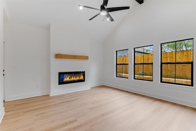 837 Birch Ln, Cottonwood Shores, TX 78657 - unfurnished living room with high vaulted ceiling, a glass covered fireplace, wood finished floors, and a ceiling fan