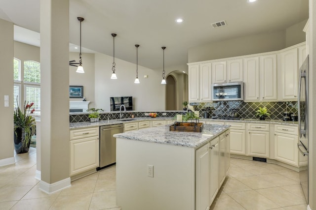 117 N Whitley Dr, Austin, TX 78738 - kitchen featuring appliances with stainless steel finishes, decorative backsplash, a center island, arched walkways, and light stone countertops