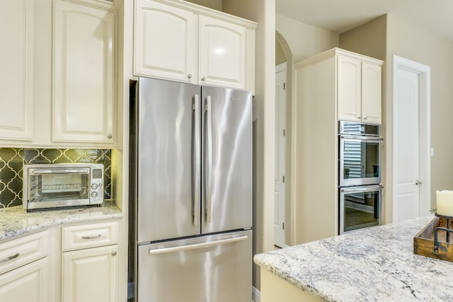 117 N Whitley Dr, Austin, TX 78738 - kitchen with stainless steel appliances, light stone countertops, tasteful backsplash, arched walkways, and white cabinets