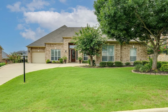 117 N Whitley Dr, Austin, TX 78738 - view of front facade with brick siding, driveway, a front lawn, an attached garage, and a shingled roof