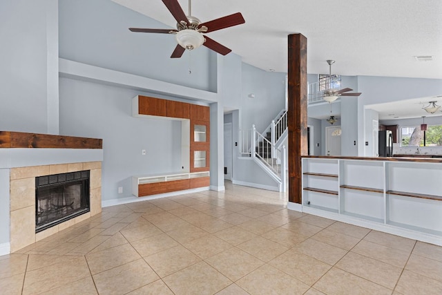 1102 Forest Oaks Path, Cedar Park, TX 78613 - unfurnished living room featuring a ceiling fan, high vaulted ceiling, light tile patterned floors, stairs, and a tile fireplace