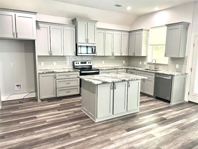 108 W Keamuku Ct, Bastrop, TX 78602 - kitchen featuring stainless steel appliances, gray cabinetry, vaulted ceiling, dark wood-style flooring, and tasteful backsplash