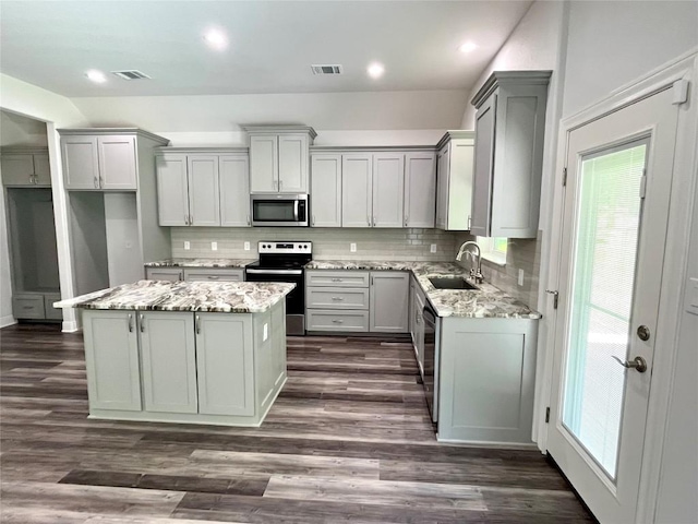 108 W Keamuku Ct, Bastrop, TX 78602 - kitchen with appliances with stainless steel finishes, gray cabinetry, a center island, tasteful backsplash, and recessed lighting