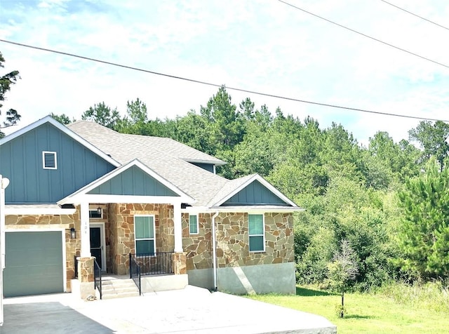 108 W Keamuku Ct, Bastrop, TX 78602 - view of front of property featuring roof with shingles, stone siding, board and batten siding, driveway, and covered porch