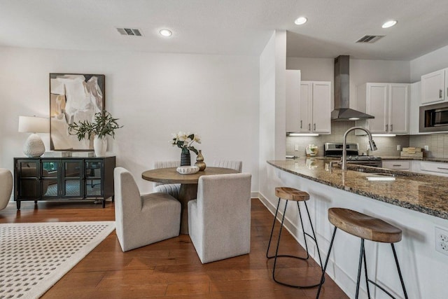2520 Bluebonnet Ln Unit 48, Austin, TX 78704 - kitchen with wall chimney exhaust hood, stainless steel appliances, dark stone countertops, white cabinetry, and dark wood-style flooring
