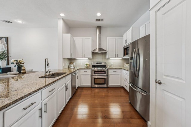 2520 Bluebonnet Ln Unit 48, Austin, TX 78704 - kitchen with stainless steel appliances, wall chimney range hood, white cabinetry, light stone counters, and recessed lighting