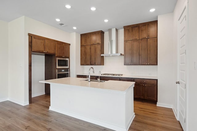 1754 Sawmill Xing, Round Rock, TX 78665 - kitchen with wall chimney exhaust hood, appliances with stainless steel finishes, tasteful backsplash, wood finished floors, and light countertops