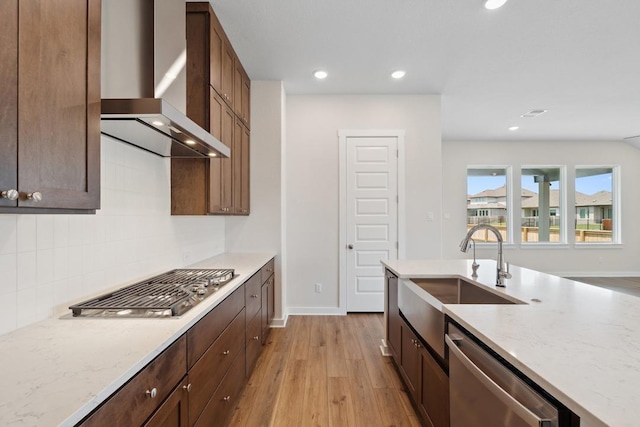 1754 Sawmill Xing, Round Rock, TX 78665 - kitchen featuring wall chimney exhaust hood, stainless steel appliances, light wood-type flooring, light stone counters, and backsplash
