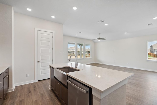 1754 Sawmill Xing, Round Rock, TX 78665 - kitchen with stainless steel dishwasher, wood finished floors, a ceiling fan, a center island with sink, and light stone counters