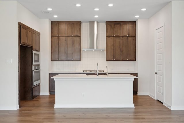 1754 Sawmill Xing, Round Rock, TX 78665 - kitchen featuring wall chimney range hood, stainless steel appliances, an island with sink, decorative backsplash, and recessed lighting