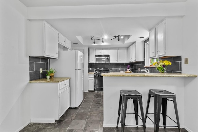 1305 Doonesbury Dr, Austin, TX 78758 - kitchen with stainless steel microwave, range with gas cooktop, a peninsula, freestanding refrigerator, and white cabinets