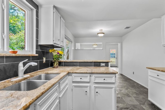 1305 Doonesbury Dr, Austin, TX 78758 - kitchen with decorative backsplash, healthy amount of natural light, a peninsula, and white cabinets