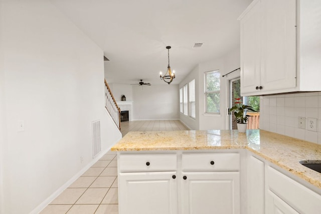 2732 Cascade Falls Dr, Austin, TX 78738 - kitchen with a peninsula, a chandelier, backsplash, a ceiling fan, and white cabinetry