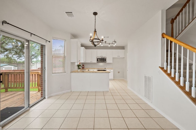 2732 Cascade Falls Dr, Austin, TX 78738 - kitchen with stainless steel microwave, a chandelier, a peninsula, light countertops, and backsplash