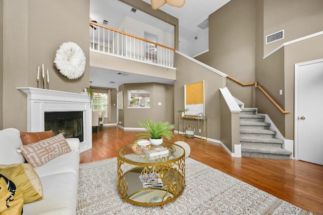 8305 Hillrock Dr, Round Rock, TX 78681 - living room featuring a towering ceiling, wood finished floors, stairway, and a glass covered fireplace