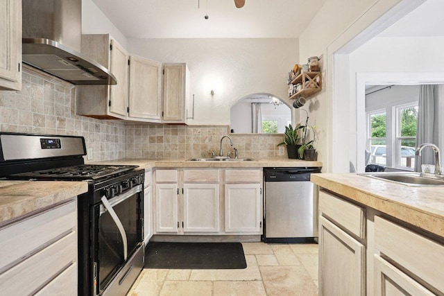 1916 Pecan St, Bastrop, TX 78602 - kitchen featuring gas stove, dishwasher, wall chimney exhaust hood, stone tile flooring, and light countertops