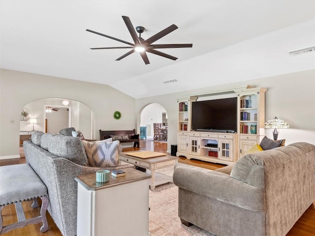 living area with arched walkways, a ceiling fan, lofted ceiling, and wood finished floors