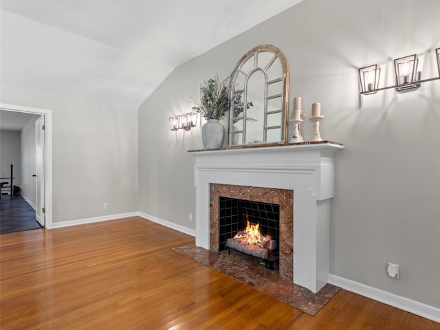 unfurnished living room with a high end fireplace, wood finished floors, and vaulted ceiling