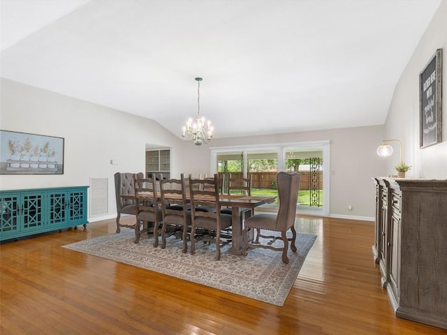 dining area with lofted ceiling, a chandelier, and wood finished floors
