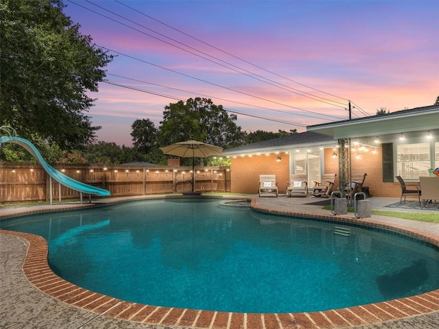 view of pool featuring a patio, a water slide, and a fenced backyard