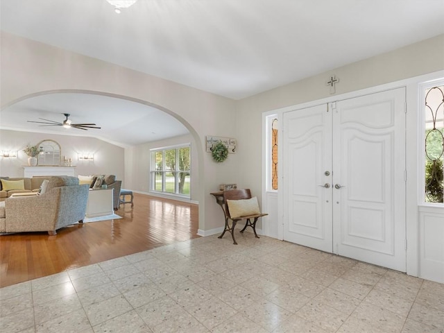 foyer featuring arched walkways, a ceiling fan, and vaulted ceiling