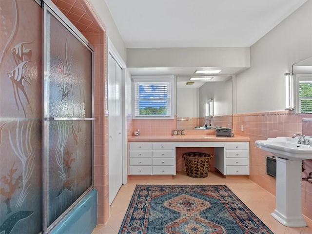 bathroom with tile walls, tile patterned floors, shower / bath combination with glass door, and wainscoting
