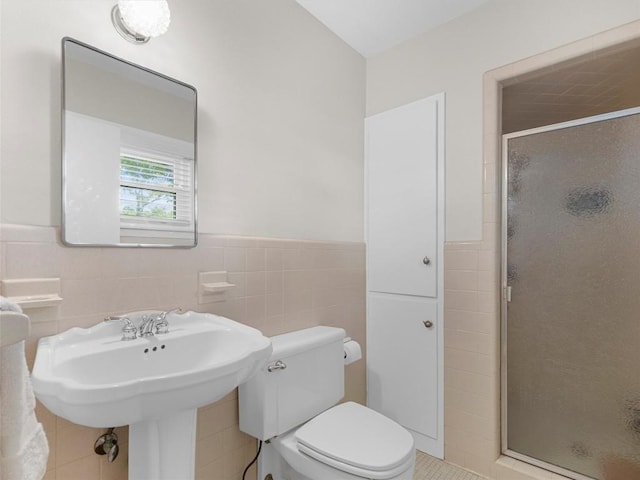 full bath featuring tile walls, a shower stall, and a wainscoted wall