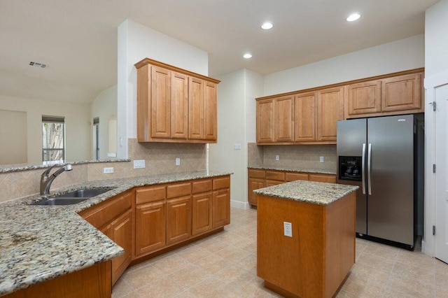 105 Outcrop View Ln, Austin, TX 78738 - kitchen featuring stainless steel fridge, light stone countertops, backsplash, brown cabinets, and recessed lighting