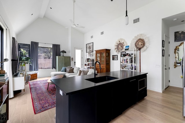 5509 Clay Ave Unit 2, Austin, TX 78756 - kitchen with dark countertops, high vaulted ceiling, light wood-type flooring, open floor plan, and an island with sink