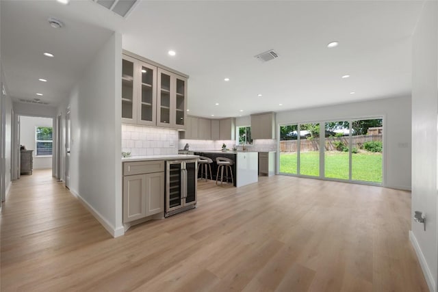 1101 Floradale Dr, Austin, TX 78753 - kitchen featuring wine cooler, light wood-style floors, tasteful backsplash, light countertops, and healthy amount of natural light