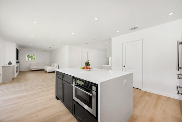1101 Floradale Dr, Austin, TX 78753 - kitchen featuring light wood-style floors, a kitchen island, light countertops, recessed lighting, and dark cabinetry