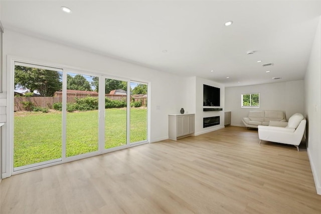 1101 Floradale Dr, Austin, TX 78753 - unfurnished living room featuring a glass covered fireplace, light wood-style flooring, and recessed lighting