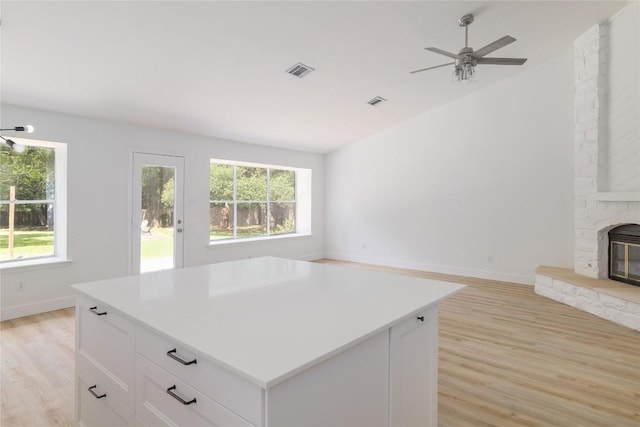 2502 W Messick Loop, Round Rock, TX 78681 - kitchen with light wood finished floors, open floor plan, ceiling fan, a kitchen island, and white cabinetry
