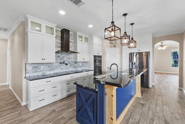 15020 Hero Way W, Leander, TX 78641 - kitchen featuring wall chimney range hood, stainless steel appliances, light wood finished floors, crown molding, and backsplash