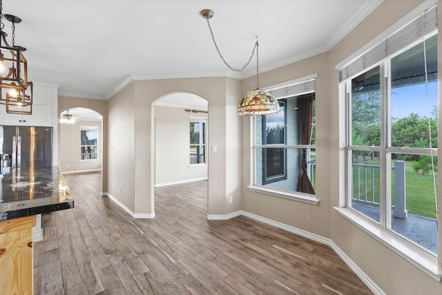 15020 Hero Way W, Leander, TX 78641 - unfurnished dining area featuring arched walkways, wood finished floors, ornamental molding, and a chandelier