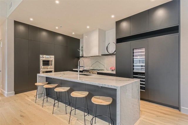 1315 W 9th St Unit B, Austin, TX 78703 - kitchen with light wood-style floors, a kitchen breakfast bar, modern cabinets, light stone counters, and recessed lighting