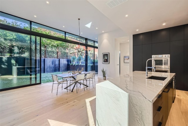 1315 W 9th St Unit B, Austin, TX 78703 - kitchen with modern cabinets, expansive windows, dark cabinets, light wood-style flooring, and recessed lighting
