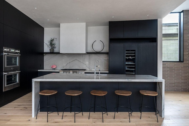 1315 W 9th St Unit B, Austin, TX 78703 - kitchen with double oven, modern cabinets, dark cabinetry, and light wood-style flooring