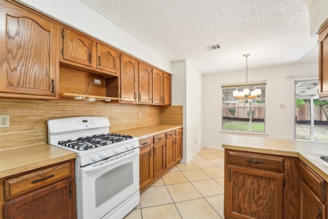 12404 Wycliff Ln, Austin, TX 78727 - kitchen featuring white gas range oven, decorative backsplash, a chandelier, light countertops, and a textured ceiling