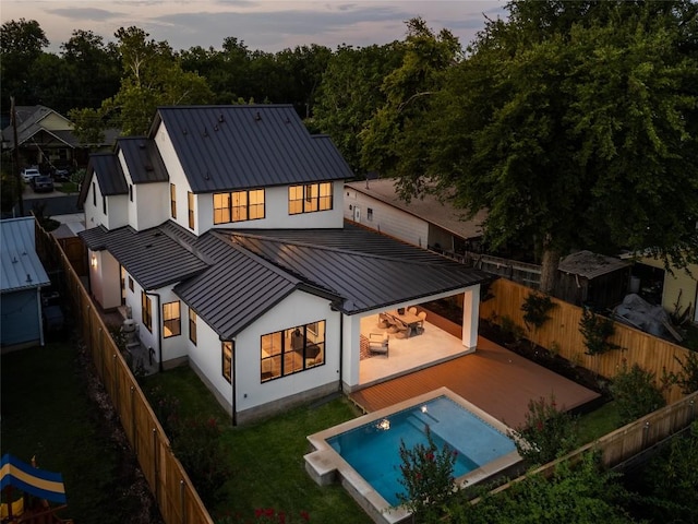 1703 Madison, Austin, TX 78757 - back of property at dusk featuring a standing seam roof, a metal roof, stucco siding, and a fenced backyard