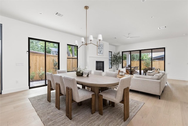 1703 Madison, Austin, TX 78757 - dining space with light wood-type flooring, a glass covered fireplace, and a chandelier