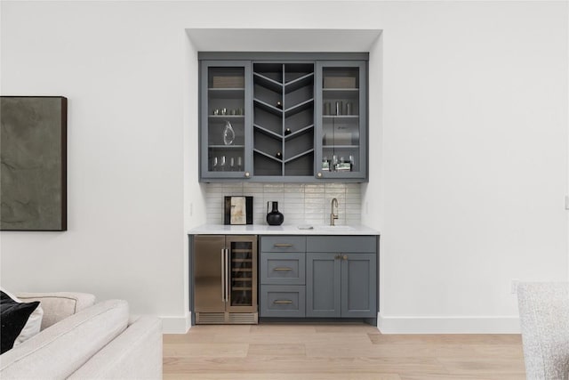 1703 Madison, Austin, TX 78757 - indoor wet bar featuring wine cooler, light wood-type flooring, tasteful backsplash, and fridge