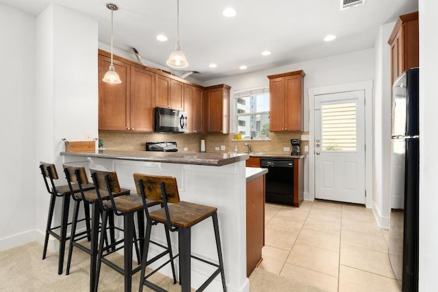 1601 Miriam Ave Unit 100, Austin, TX 78702 - kitchen featuring black appliances, a peninsula, decorative backsplash, recessed lighting, and a breakfast bar area